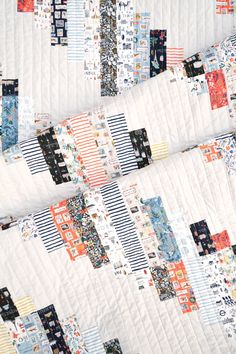 a close up of a quilt on a bed with many different colors and patterns in it