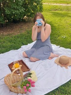 a woman sitting on a blanket holding up a camera to her face while taking pictures