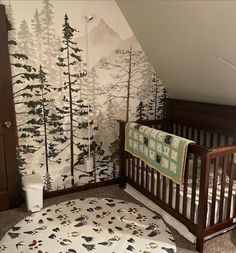 a baby's room with a crib and wallpaper that has trees on it