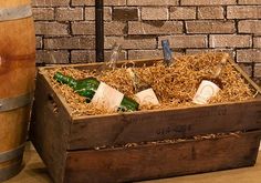 a wooden box filled with bottles of wine next to a brick wall and wood barrel