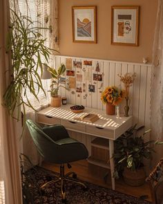 a room with a desk, chair and pictures on the wall above it is also a potted plant