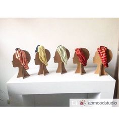 five different types of head coverings sitting on top of a white shelf in front of a wall