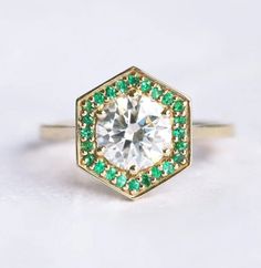 a diamond and emerald ring on a white surface