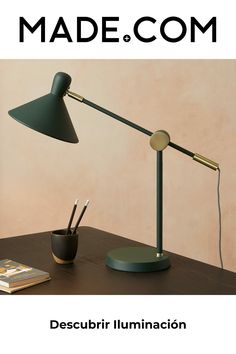 a desk lamp sitting on top of a table next to a cup and pen holder