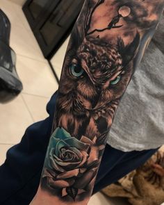 an owl with blue eyes and a rose tattoo on the left arm is shown in black and grey