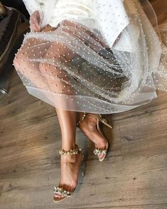 a woman is sitting on the floor wearing high heels and a white dress with polka dots