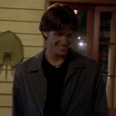 the young man smiles as he stands in front of a door