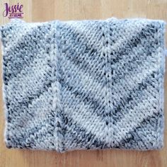 a gray and white knitted dishcloth sitting on top of a wooden table next to a knife