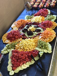 many different types of fruit are arranged on a long blue table with black cloths