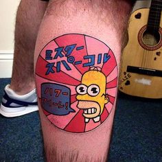 a man with a cartoon character tattoo on his leg, next to an acoustic guitar