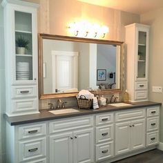 a bathroom with double sinks and large mirror over it's counter top, along with white cabinets