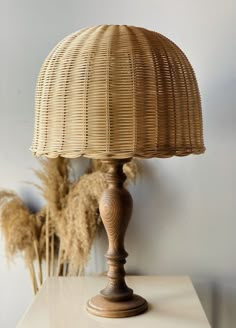 a wicker lamp sitting on top of a table next to some dried flowers and grass