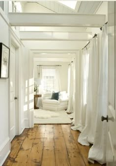 a white room with wood floors and curtains