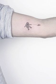 a person's arm with a small spaceman tattoo on the left inner arm