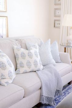 a living room with white couches and blue throw pillows on top of the couch