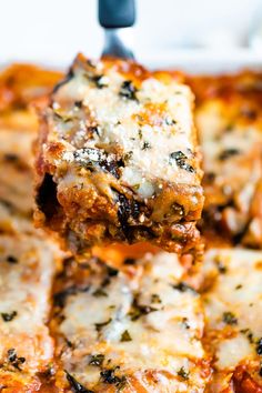 a spatula is lifting up some lasagna from the casserole dish