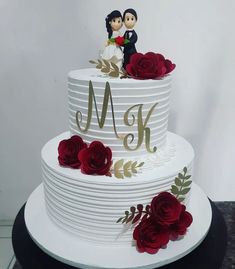 a wedding cake decorated with red roses and the bride and groom topper on it