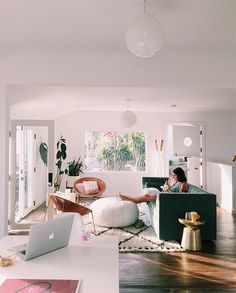 a woman sitting on top of a couch in a living room next to a laptop computer