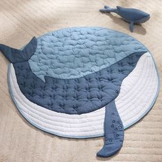 a blue whale rug on the floor next to a toy shark laying on it's side