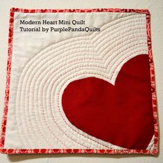 a close up of a red heart on a white quilted piece of cloth with the words modern heart mini quilt