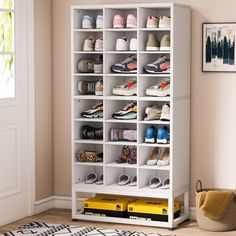 a white bookcase filled with lots of shoes next to a yellow box on the floor