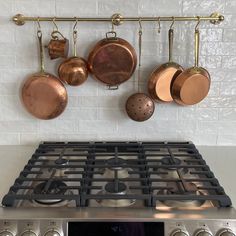 pots and pans are hanging on the wall above an oven