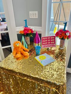 there is a gold sequin table cloth with flowers on it and a stuffed animal