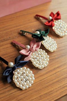 three hair clips with bows and pearls on them sitting on a table next to each other