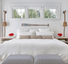 a bed with white linens and pillows in a bedroom next to two lamps on either side of the bed