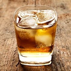 a glass filled with ice sitting on top of a wooden table