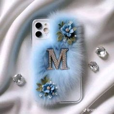 an iphone case with the letter m on it and flowers in front of white satin