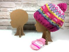 two knitted hats on mannequin heads, one pink and the other blue