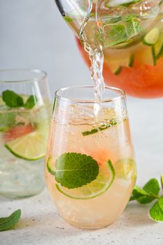 a pitcher pouring water into a glass filled with lemonade and mint