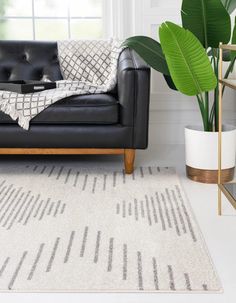 a living room with a black leather couch and white rug