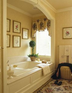 a bath room with a tub a sink and pictures on the wall