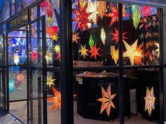 a store front window with christmas lights hanging from it's sides and stars on the windows