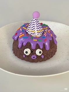 a chocolate cake with purple icing and sprinkles on it's face