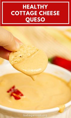 a hand holding a cracker over a bowl of cheese quesadilla soup