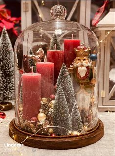 a glass cloche with candles and christmas trees in it