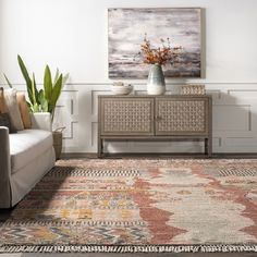 a living room scene with focus on the rug and furniture in the foreground as well as an abstract painting