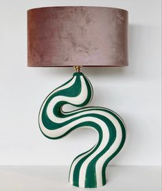 a green and white lamp sitting on top of a table next to a brown shade