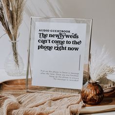 a sign sitting on top of a wooden table next to a vase filled with dry grass