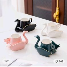 three teapots are sitting on a table next to each other, one is shaped like a swan