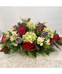 This floral centerpiece, with its combination of crimson red roses, white alstroemeria, red hypericum berries, hydrangea, and premium Christmas greens including camellia foliage, creates a stunning statement piece that embodies the spirit of celebration, making it perfect for gatherings during the holiday season. White Alstroemeria, Winter Table Centerpieces, Holiday Centerpieces Christmas, Holiday Flower Arrangements, Centerpieces Christmas, Christmas Greens, Christmas Florals, Hypericum Berries, Christmas Bouquet