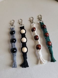 four different bracelets with beads and tassels hanging from them on a white surface