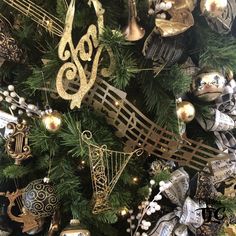 a christmas tree with ornaments and musical instruments on it's branches in gold, silver and black