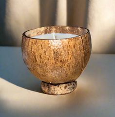 a wooden bowl filled with a candle on top of a white tablecloth covered floor