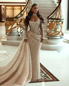 a woman in a gown and tiara standing on a carpeted floor next to stairs