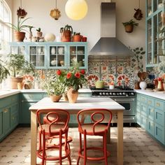 two red chairs sitting at a kitchen table with potted plants on the counter top