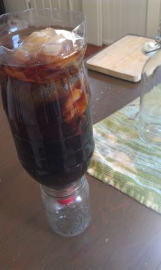 an iced beverage in a plastic cup on a wooden table next to a cutting board